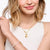 Gold-tone sun charm on a chain, worn as a necklace