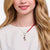 Eiffel Tower charm on a fine silver chain around the neck, with a red accent.