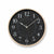 Wanduhr mit rundem schwarzem Zifferblatt und goldfarbener Einfassung, mit Zeigern.