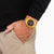 Herrenuhr in Goldfarbe am Handgelenk mit schwarzem Zifferblatt und Metallarmband
