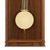 Wood wall clock detail: round pendulum with gold-colored brackets in front of brown wood frame