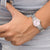 Women's watch on wrist with silver metal band and pink dial
