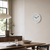 Weiße runde Wanduhr an der Wand mit schwarzen Zeigern und gut lesbaren Ziffern.