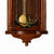 Detail der braunen Holz-Wanduhr: goldfarbene Glocke und florale Ornamentverzierungen