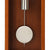 Detail view: Metal pendulum and large white pendulum disc of the wall clock in a wooden case.