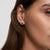 alt
Silver colored hoop earring with a small, dangling, silver colored charm.