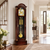 Grandfather clock in dark wood case with large dial, pendulum, and gold weights