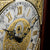 Clock face of the grandfather clock with Roman numerals, gold-embellished and blackened hands