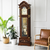 Wooden grandfather clock with round dial and pendulum in glass insert