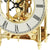 Goldene Tischuhr mit offenliegendem Uhrwerk und römischen Ziffern, schwarze Zeiger
