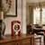 Red tabletop clock on a wooden dresser with a round dial and a spherical pendulum