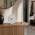 Table clock on wooden surface: gray dial with black hands and silver base