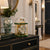 Mechanical table clock with glass dome, golden columns, and green base, round dial
