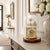 Table clock under glass dome on a light sideboard, golden clockwork and brown base