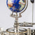 Detail of the clockwork with brass gear, metal rods, and globe attachment in blue
