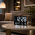 Digital clock on coffee table, black frame, LED display for time and temperature/humidity.