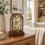 Wooden table clock on a wooden table, glass arch, gold-colored clockwork with Roman numerals