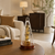 Table clock with glass dome and golden movement on a round table, brown wooden base