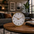 Table clock on wooden table: round brass casing with white dial and gold hands