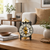 Mechanical table clock with visible gold-colored movement, round dial on a wooden sideboard