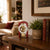 Red tabletop clock on dark dresser next to plants, round dial with clockwork