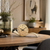 Table clock with round dial, curved wooden base in brass look and black hands