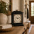 Black table clock with floral dial and gold-colored carrying handle on wood