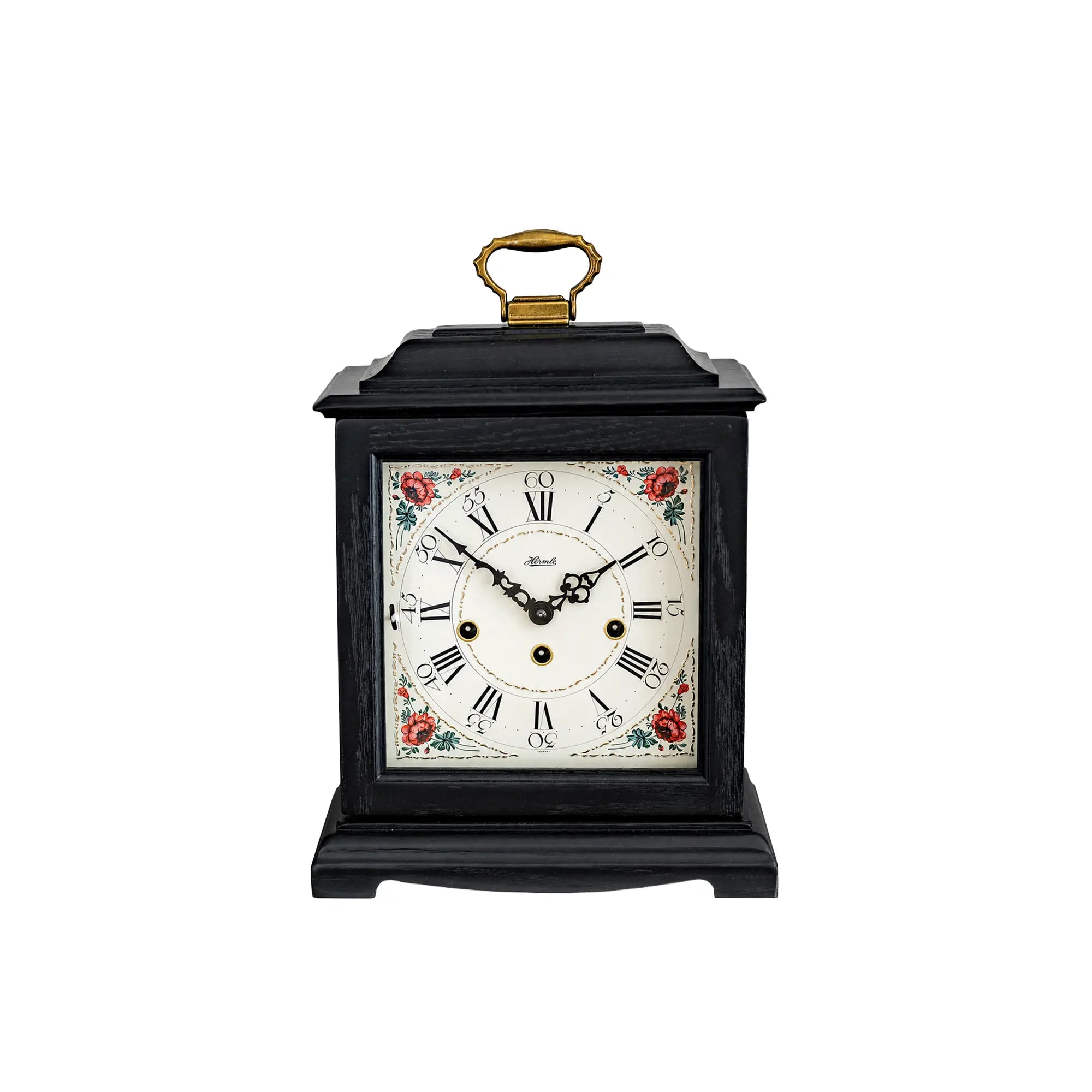 Black table clock with floral dial and gold-colored carrying handle, mechanical movement