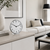 Table clock with white dial, black numerals, and chrome frame on cabinet