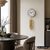 Wanduhr mit rundem Zifferblatt, goldfarbenen Gewichten und Kettenzug an der Wand