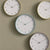 Vier analoge Wanduhr-Varianten mit hellem Zifferblatt und grünen Rahmen
