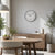 Wall clock on a light wall above a sideboard, round white dial with black numbers