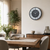 Wall clock on the wall with a black-bordered casing, marble look, and green numerals