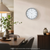 Wall clock on the wall with a round metal frame, white dial, and black numbers