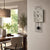 Wall clock on the wall with gray concrete look, black pendulum, and black hands