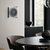 Wanduhr an Wand mit anthrazitfarbenem Ziffernblatt, quadratischem Rahmen, Glasfront