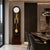 Wooden grandfather clock with round dial, gold-colored pendulum elements, and glass front