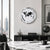 Round wall clock on the wall: silver frame, white dial, black world map