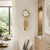 Gold-colored wall clock on the wall with hanging metal pendulums