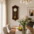 Dark wood wall clock on the wall with a round white dial and pendulum