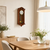 Wooden wall clock with dial, carved wooden frame, and pendulum decoration.