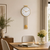 Brass wall clock with round dial and pendulum above wall mount