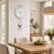 Wall clock with round dial and multiple vertical metal rods, silver ball pendulum