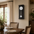 Wall clock on the wall: black casing, white dial, round pendulum weight
