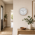 Wall clock on a light wall with a beige frame and a white dial
