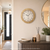 Wall clock on the wall with a beige, grainy wood-look frame and a white dial