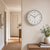 Wall clock on a light wall, round white dial with black hands and numbers