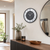 Wall clock on the wall, black frame, gray dial, green numbers, and marble