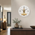 Wall clock on the wall with a white dial, black hands, and a gold movement