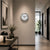Round wall clock on the wall with a white dial, silver bezel, black hands, red second hand
